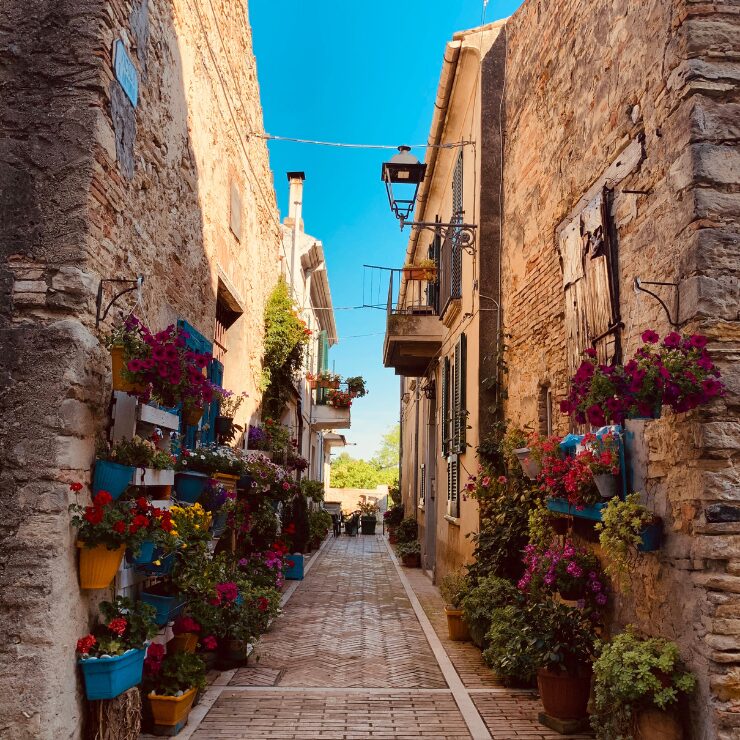 A narrow cobblestone alley in Rocca San Giovanni decorated with colourful flowers in blue wall-mounted pots