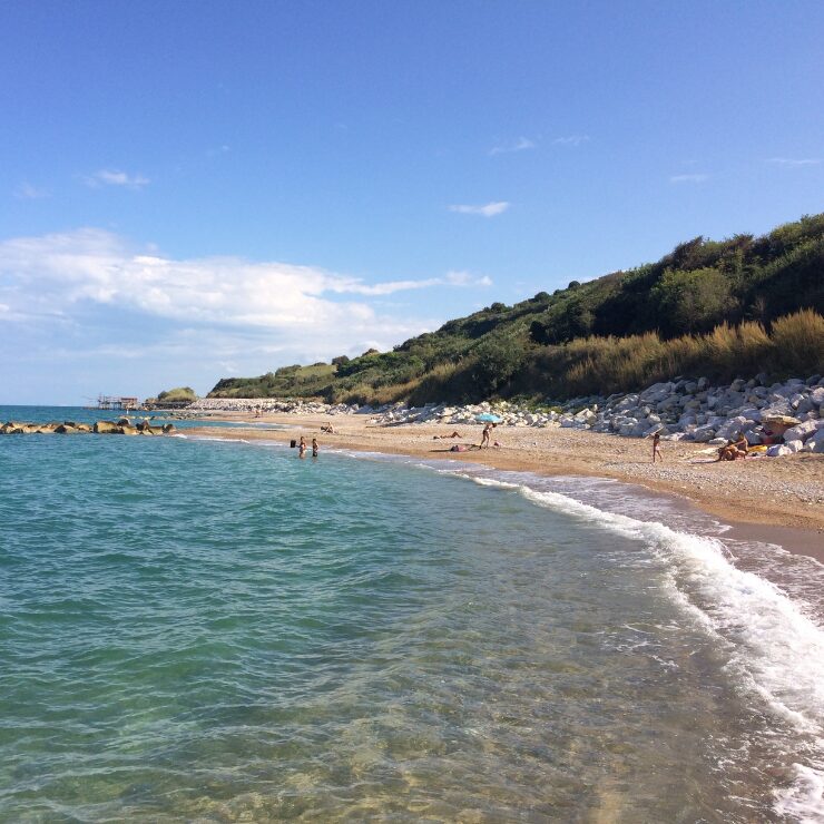 A quiet pebble and sand beach near Rocca San Giovanni with turquoise Adriatic water and a traditional trabocco fishing structure in the distance