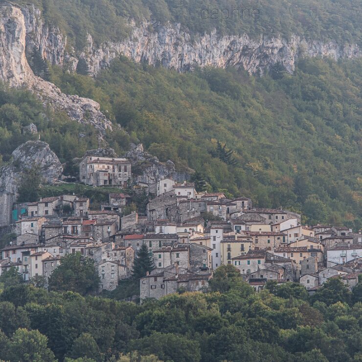 The stone village of Pietracamela nestled against a dramatic rocky cliff face and forested hillside in the Gran Sasso area of Abruzzo