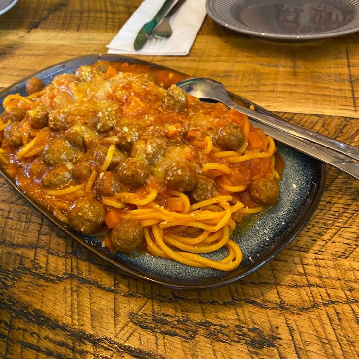 Plato generoso de espaguetis con albóndigas en salsa de tomate sobre una mesa de madera