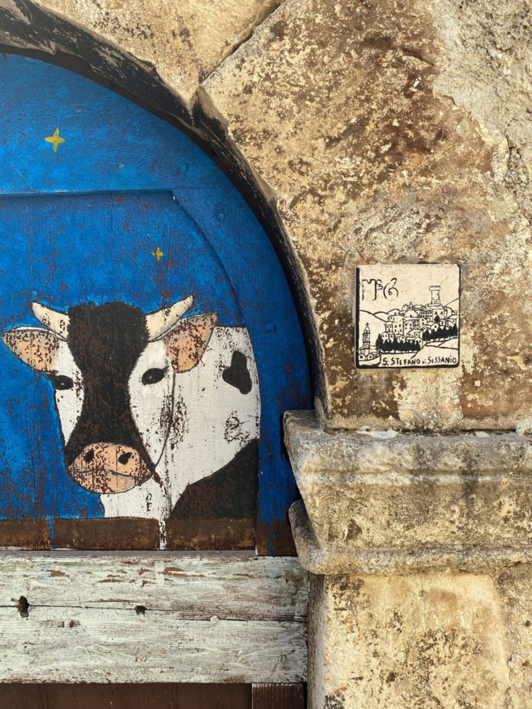 A traditional painting on a wood door next a ceramic sign