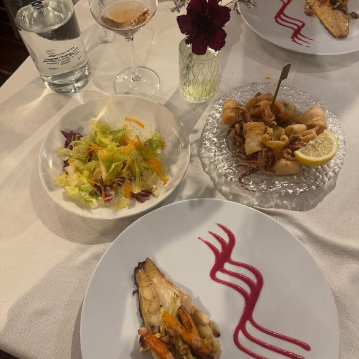 Mesa con varios platos de pescado, calamares fritos y ensalada en un restaurante trabocco en la costa de Abruzzo