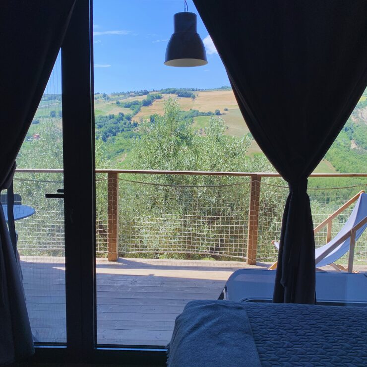 View from inside a glamping cabin looking out over olive trees and golden hills in the Abruzzo countryside