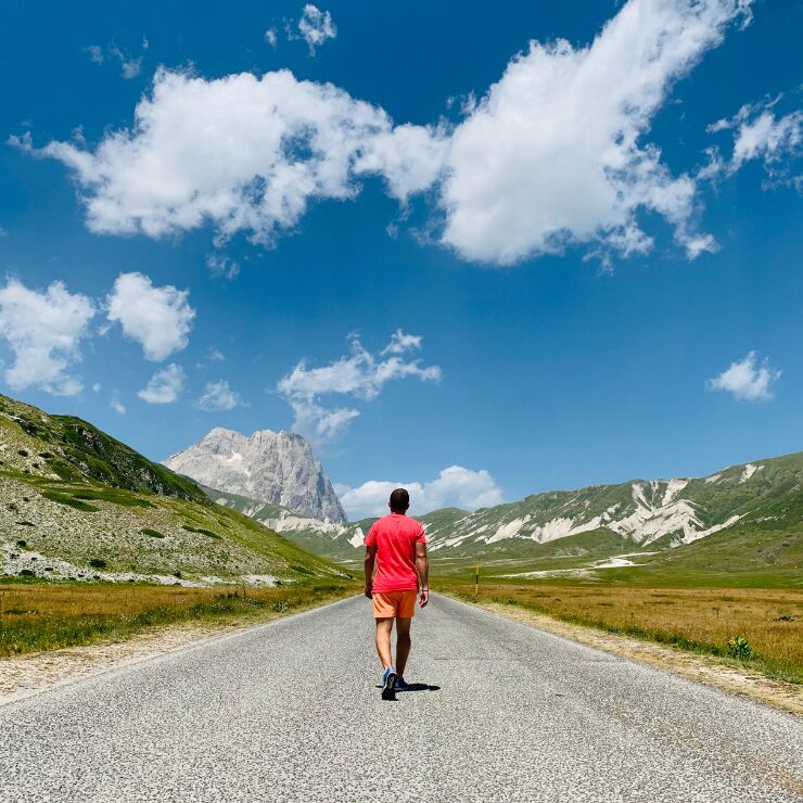 A person walking along an empty road towards the Gran Sasso massif on the Campo Imperatore plateau, Abruzzo