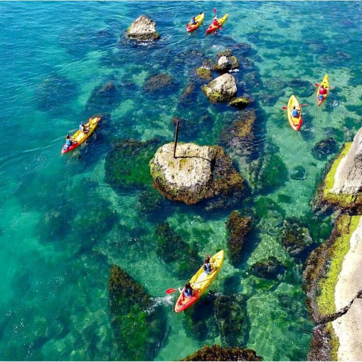Vista aérea de kayakistas remando entre aguas turquesas cristalinas y afloramientos rocosos en la costa de Abruzzo