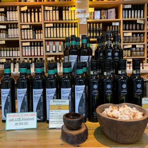 A display of Italian extra virgin olive oil bottles including DOP Masseria Trappanello and Casa Lontana brands at a speciality food shop